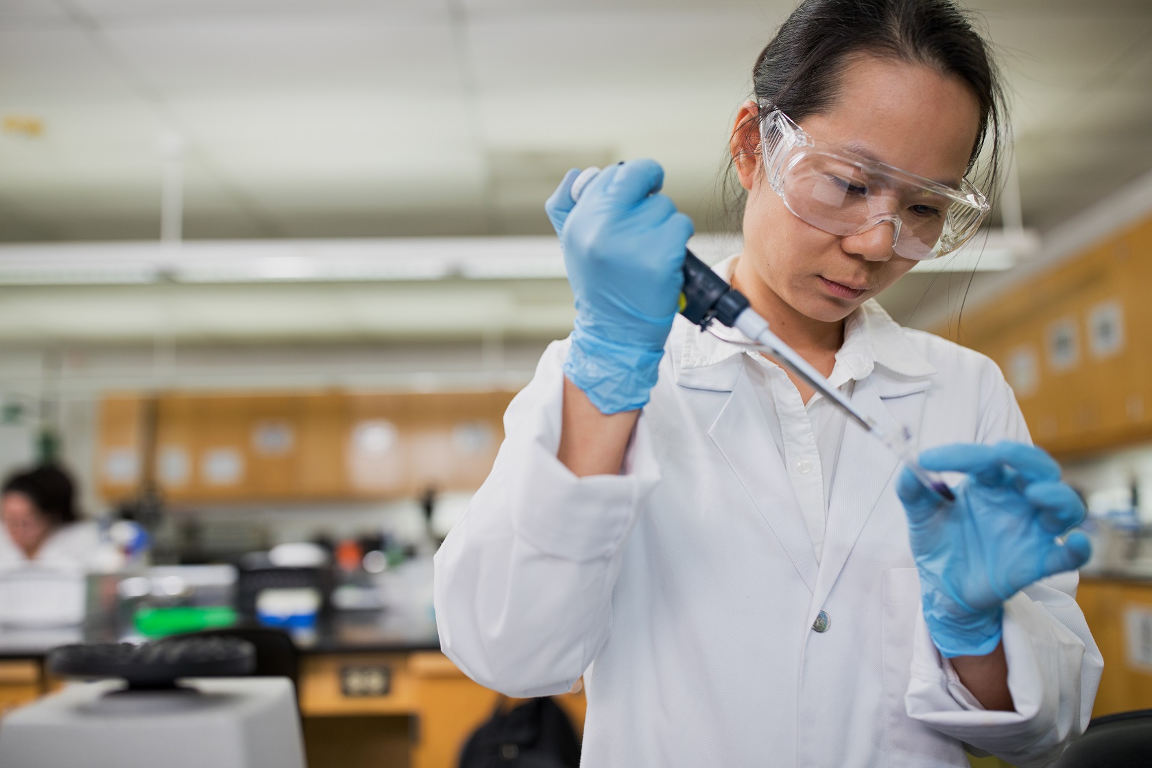 A college student in the lab using a micropipette for a lab procedure