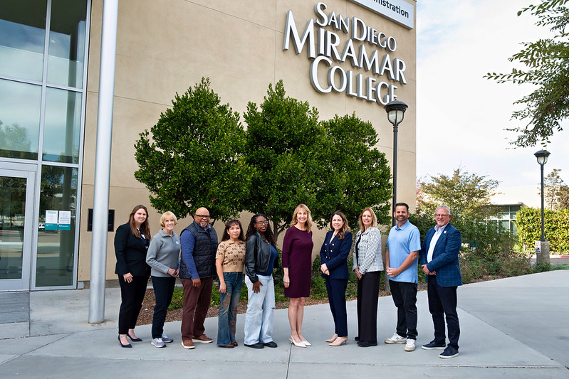Members of the Miramar College Board of Directors standing in front of a building with a sign that reads San Diego Miramar College.