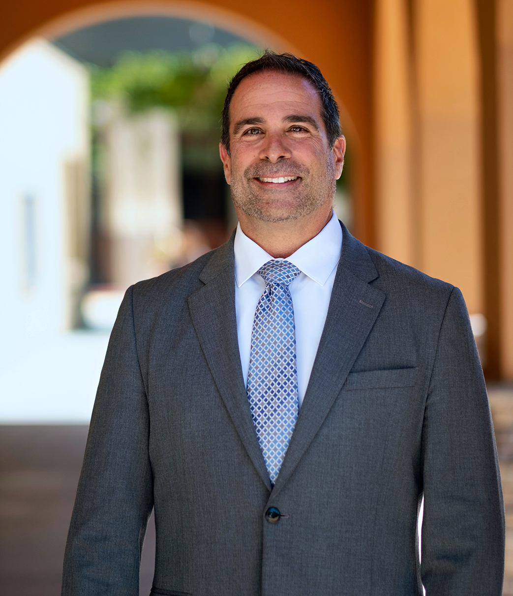 Jeffrey Orgera, Dean of Academic Services, in suit, standing in a walkway