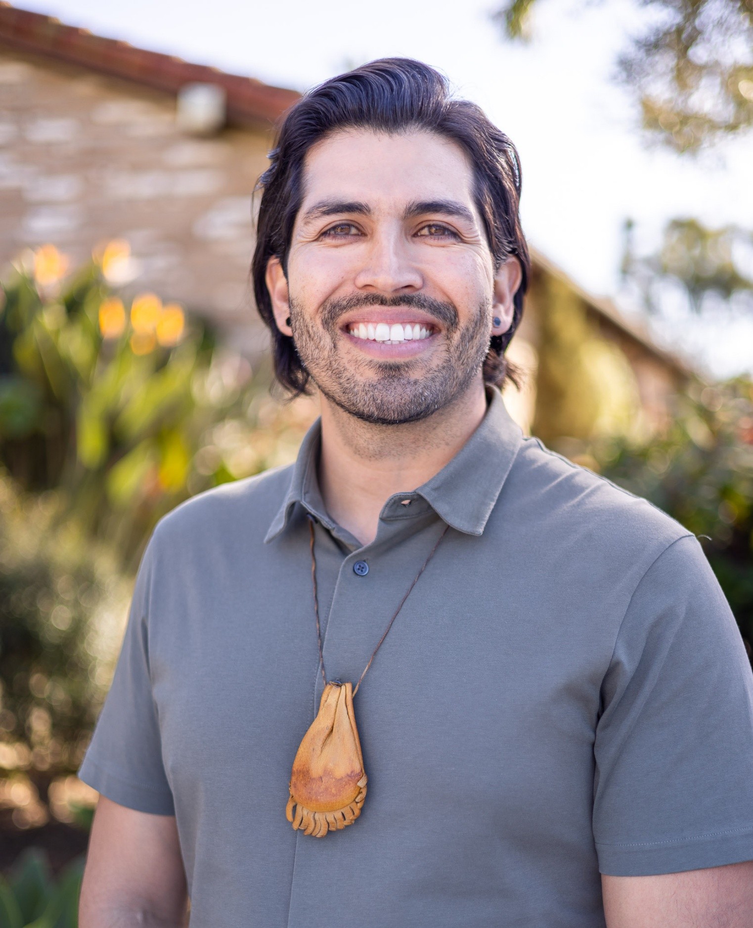 A smiling man with brown hair and a grey shirt