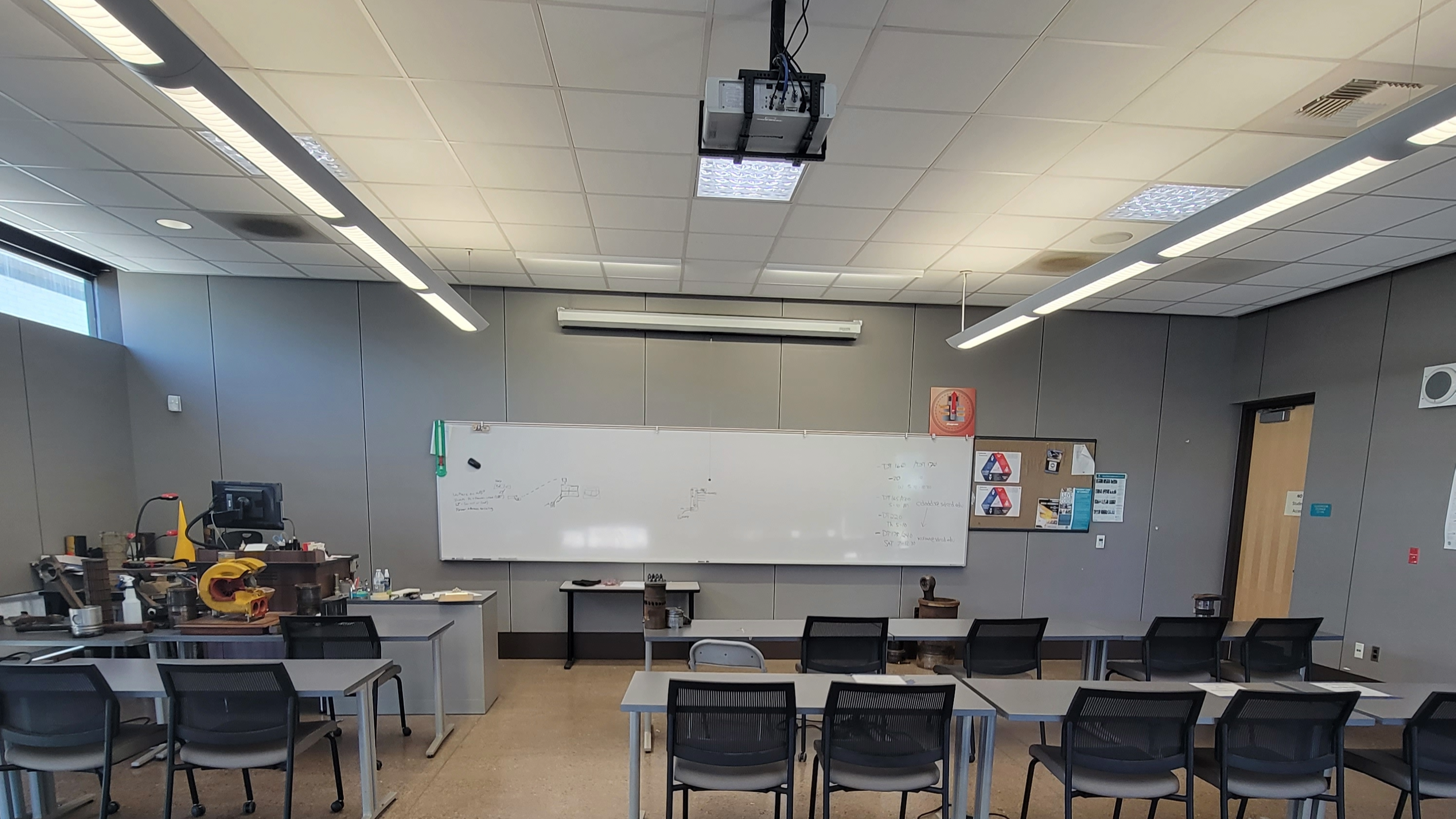 Classroom with projector, tables, and chairs. Empty.
