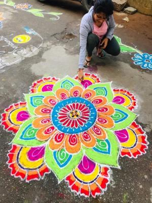 A photo of a women creating a rangoli flower design.